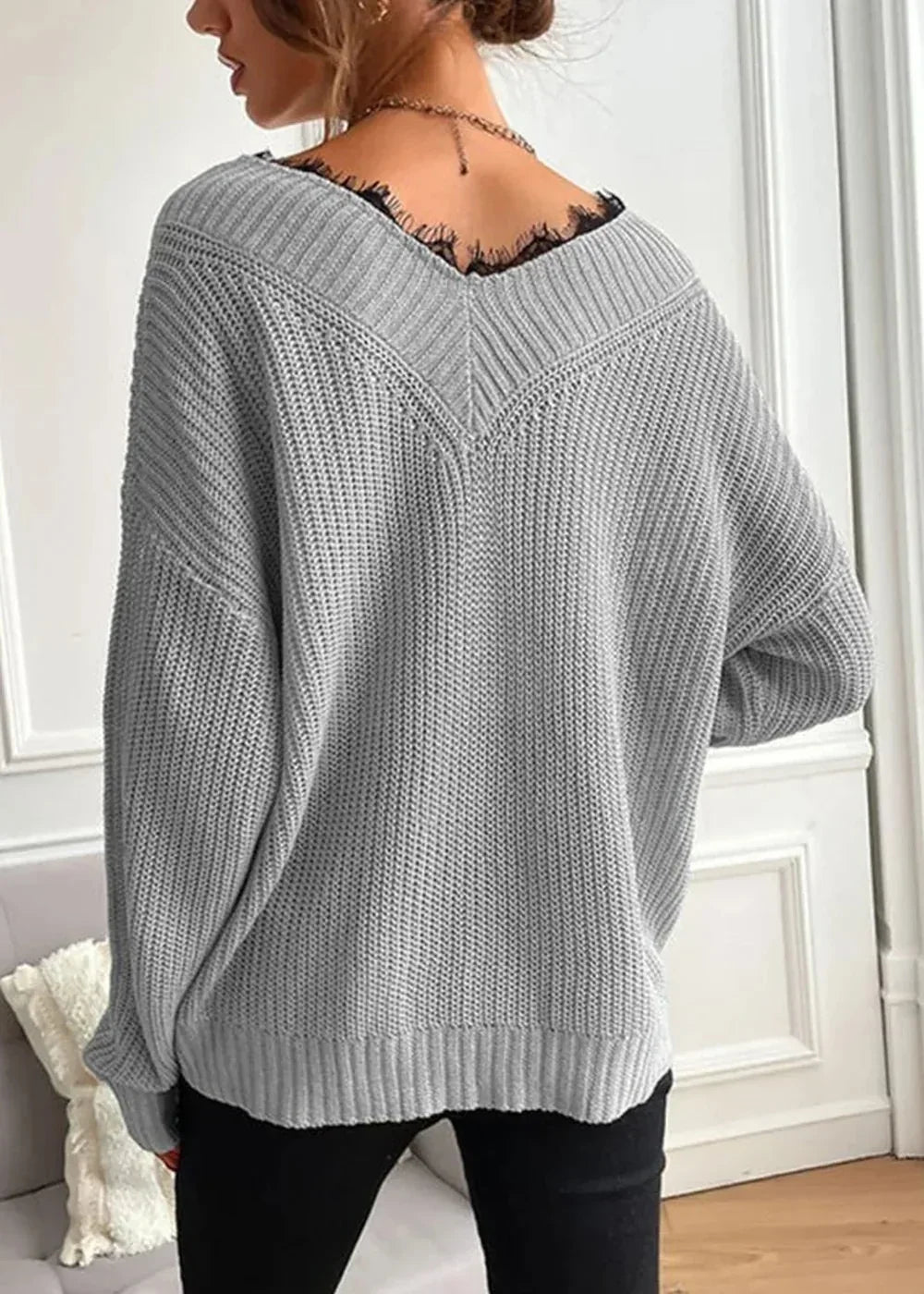 Back view of a grey knit sweater with a V-neck detailed with black lace trim.