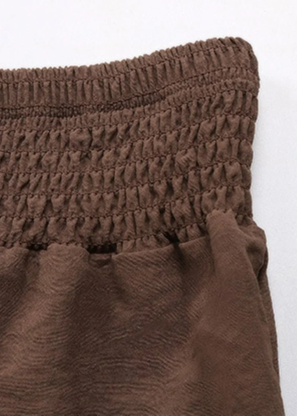 Close-up of brown smocked fabric with a textured, slightly crinkled appearance.
