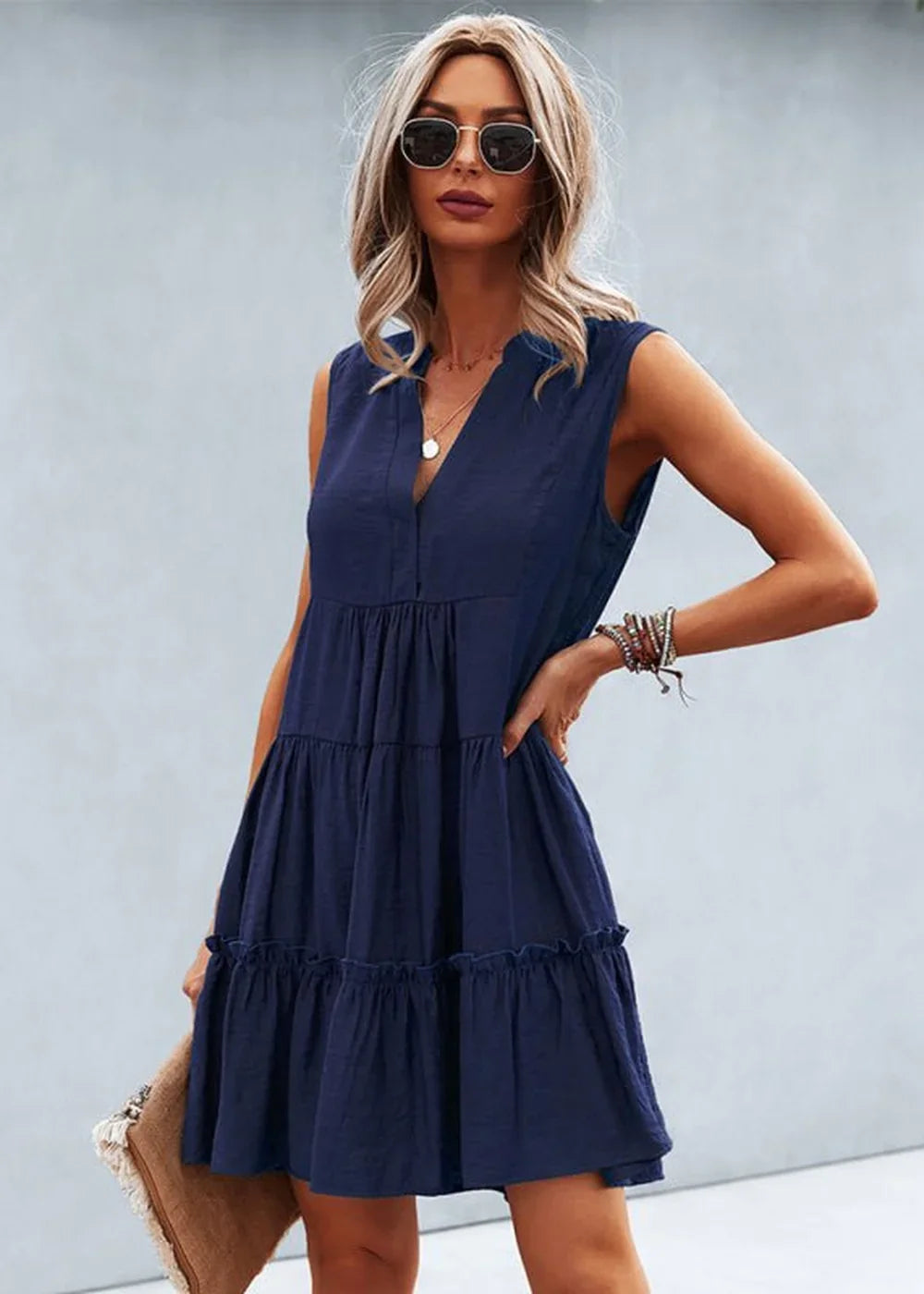 Navy blue tiered sleeveless dress with a V-neck and ruffled hem, worn by a model.