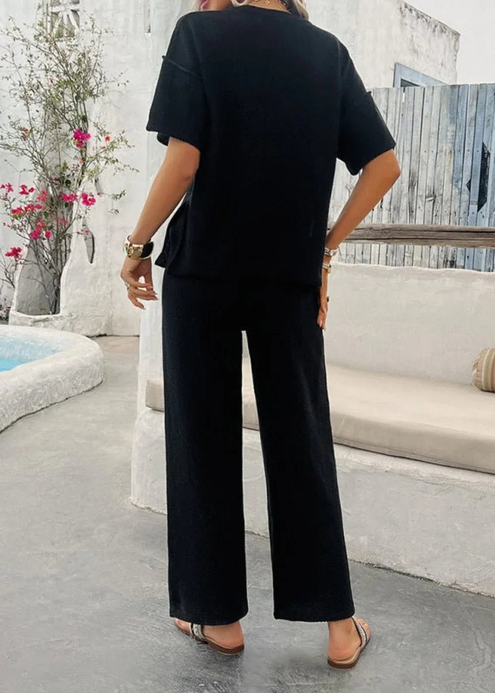 Black wide-leg pantsuit with short sleeves and a frayed hem, shown from the back.
