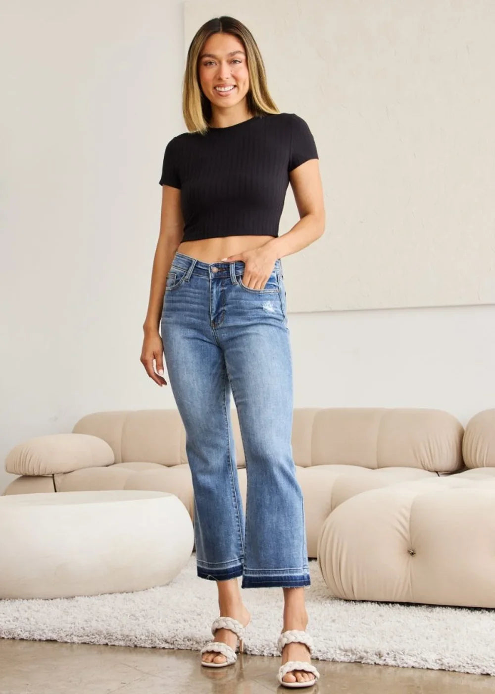 Medium wash distressed denim cropped flare jeans with a frayed hem.