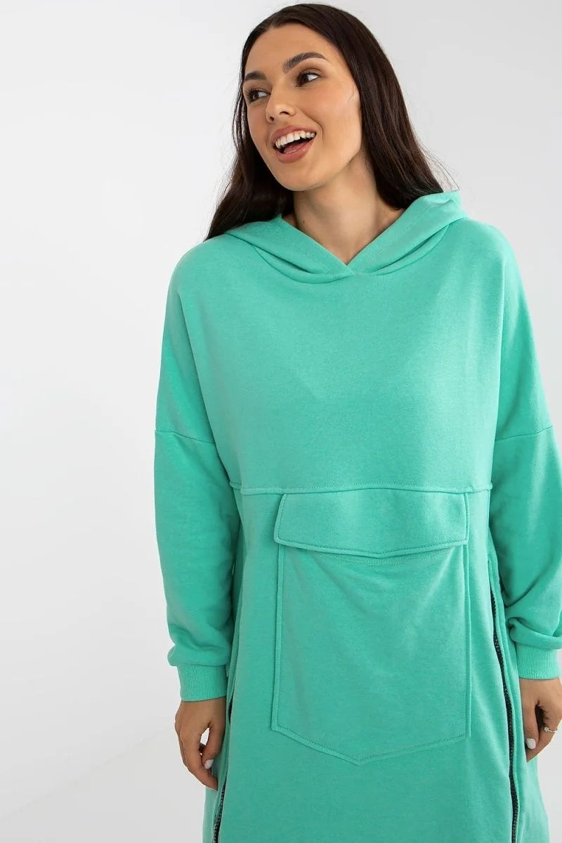 Turquoise longline hoodie dress with a large front pocket and side zippers, on a model.