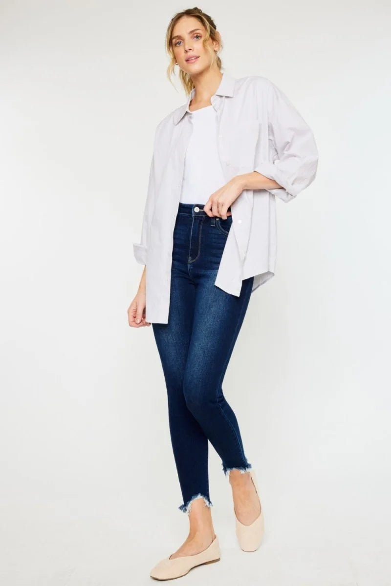 Dark wash skinny jeans with frayed hem on model.