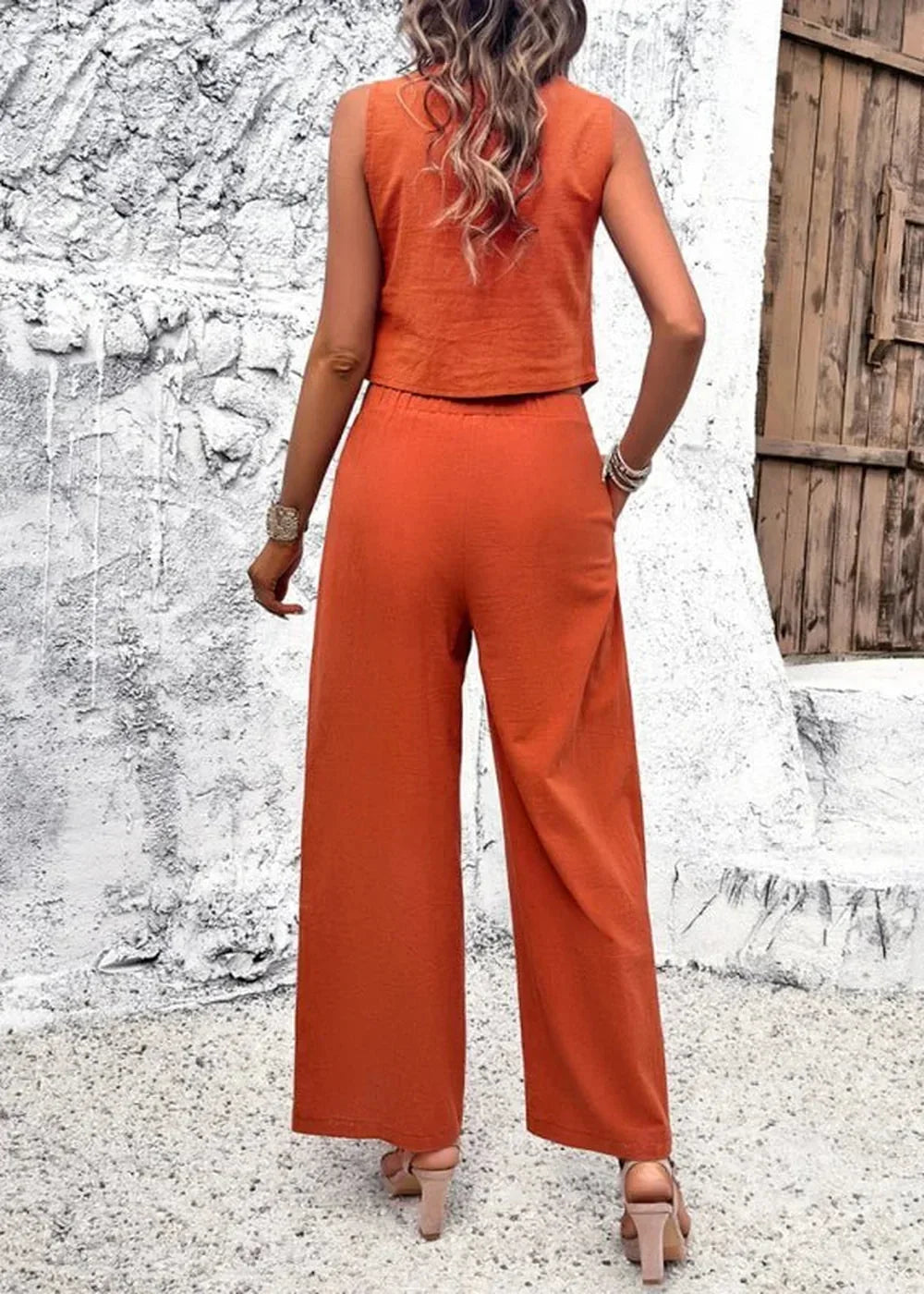 Back view of a woman wearing an orange cotton crop top and wide-leg pants, with sandals.