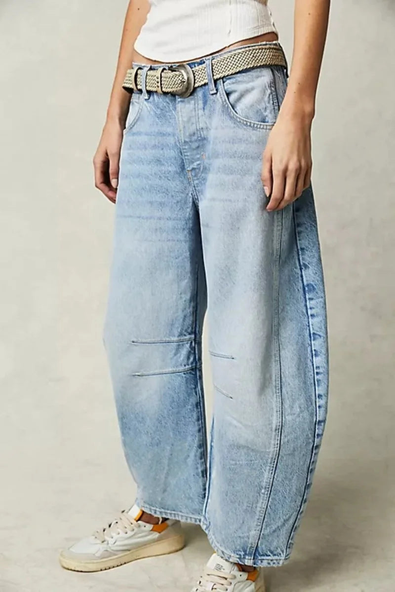 Light wash, relaxed fit denim jeans with a woven belt and white sneakers.