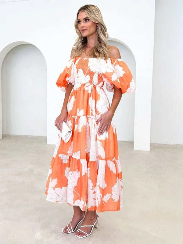 Orange off-the-shoulder tiered maxi dress with a white floral print and puff sleeves.