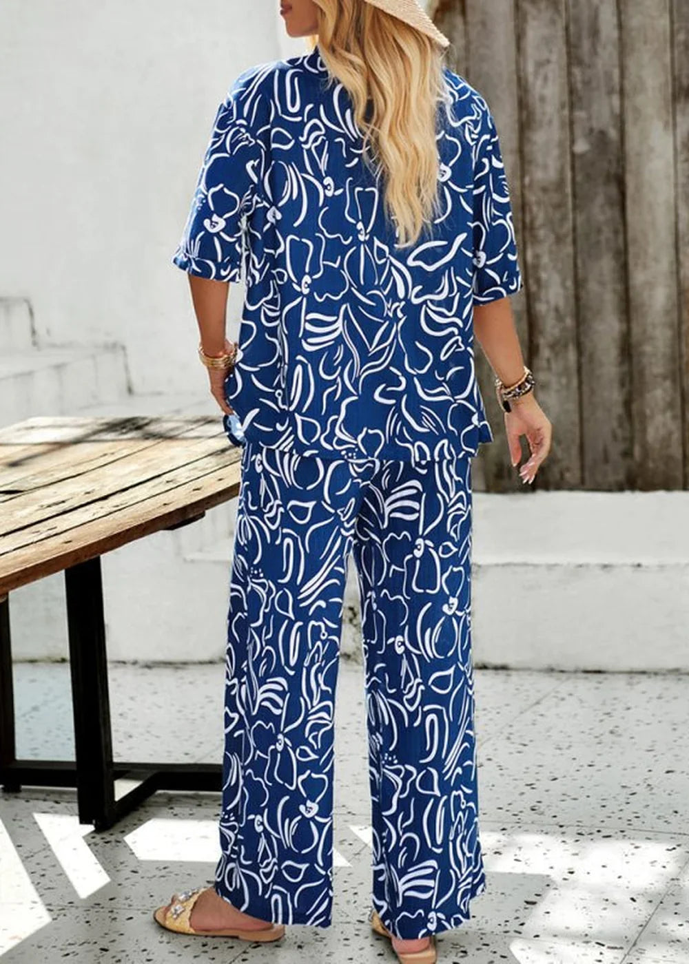 Navy blue wide-leg pants with a white abstract floral print, shown on model from the back.