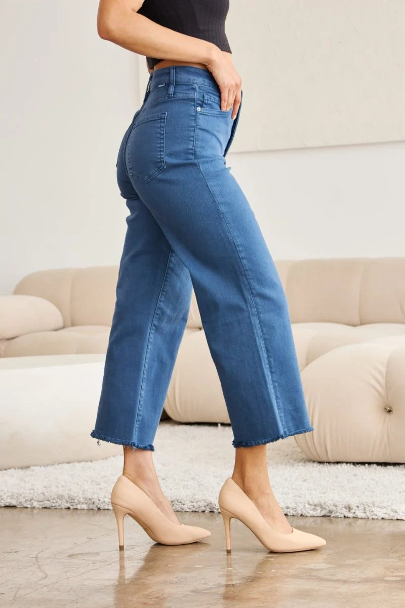 Close-up of model's hips and legs in medium-wash denim jeans with a frayed hem.