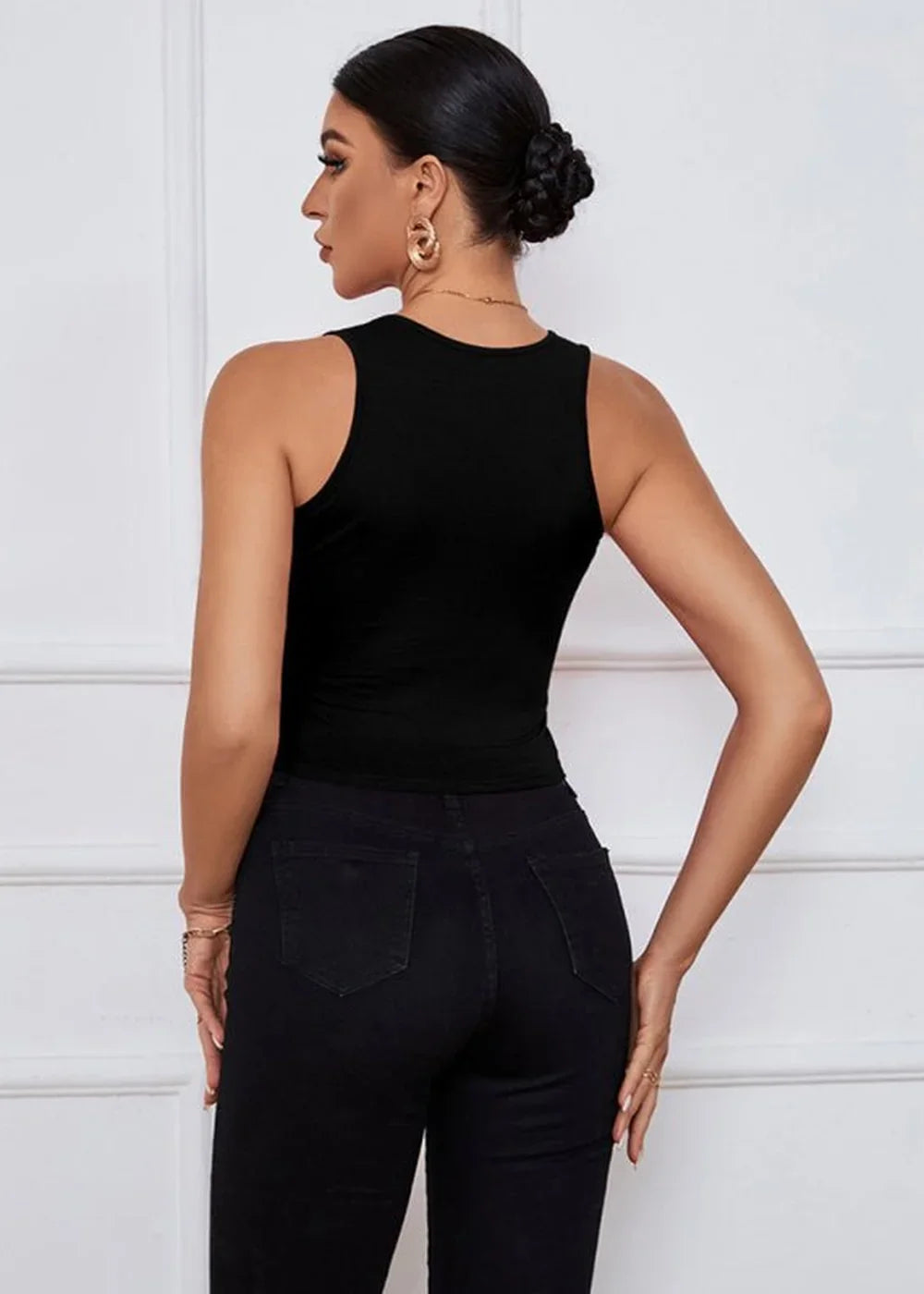 Black sleeveless crop top with a high neckline, shown from the back on a model wearing black jeans.