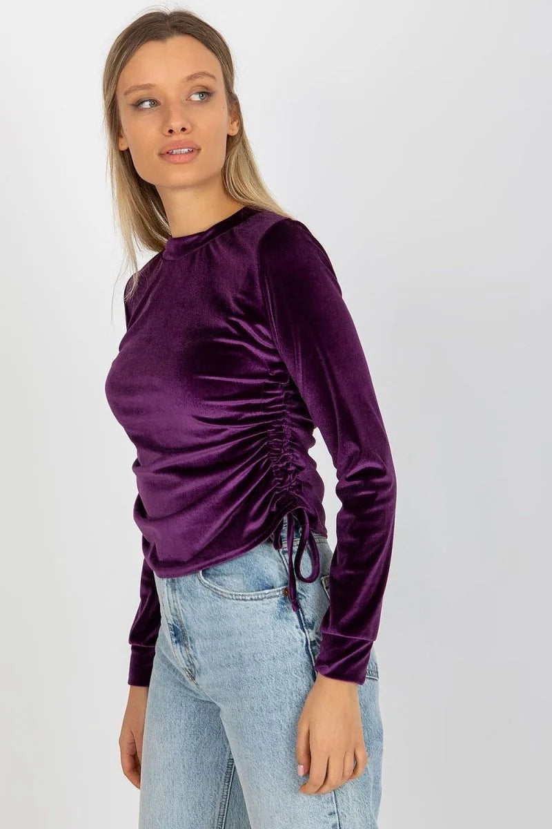 Women's plum velvet long-sleeve top with ruched side detail and drawstring, shown on a model.