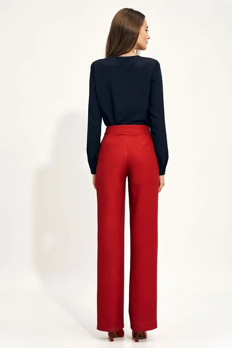 Woman in navy blue blouse and red high-rise wide-leg pants from behind.
