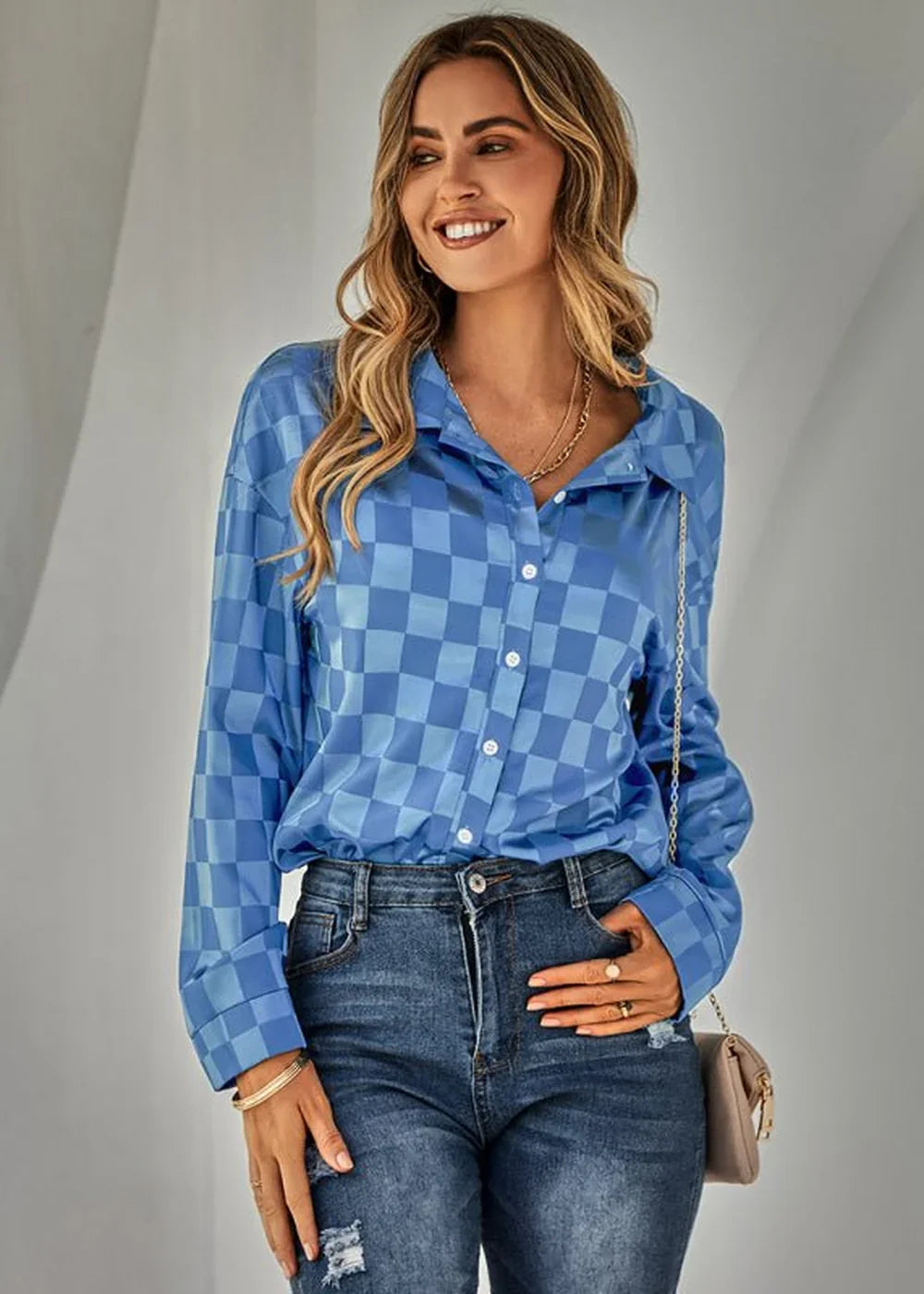 Woman wearing a blue checkered long-sleeve button-up shirt and distressed denim jeans.