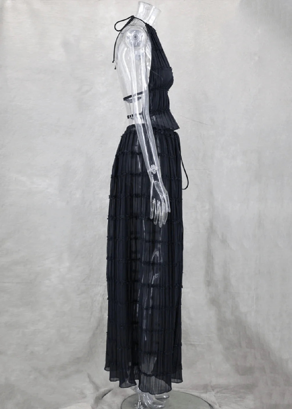 Black pleated maxi skirt suit with halter top and tie detail on mannequin.