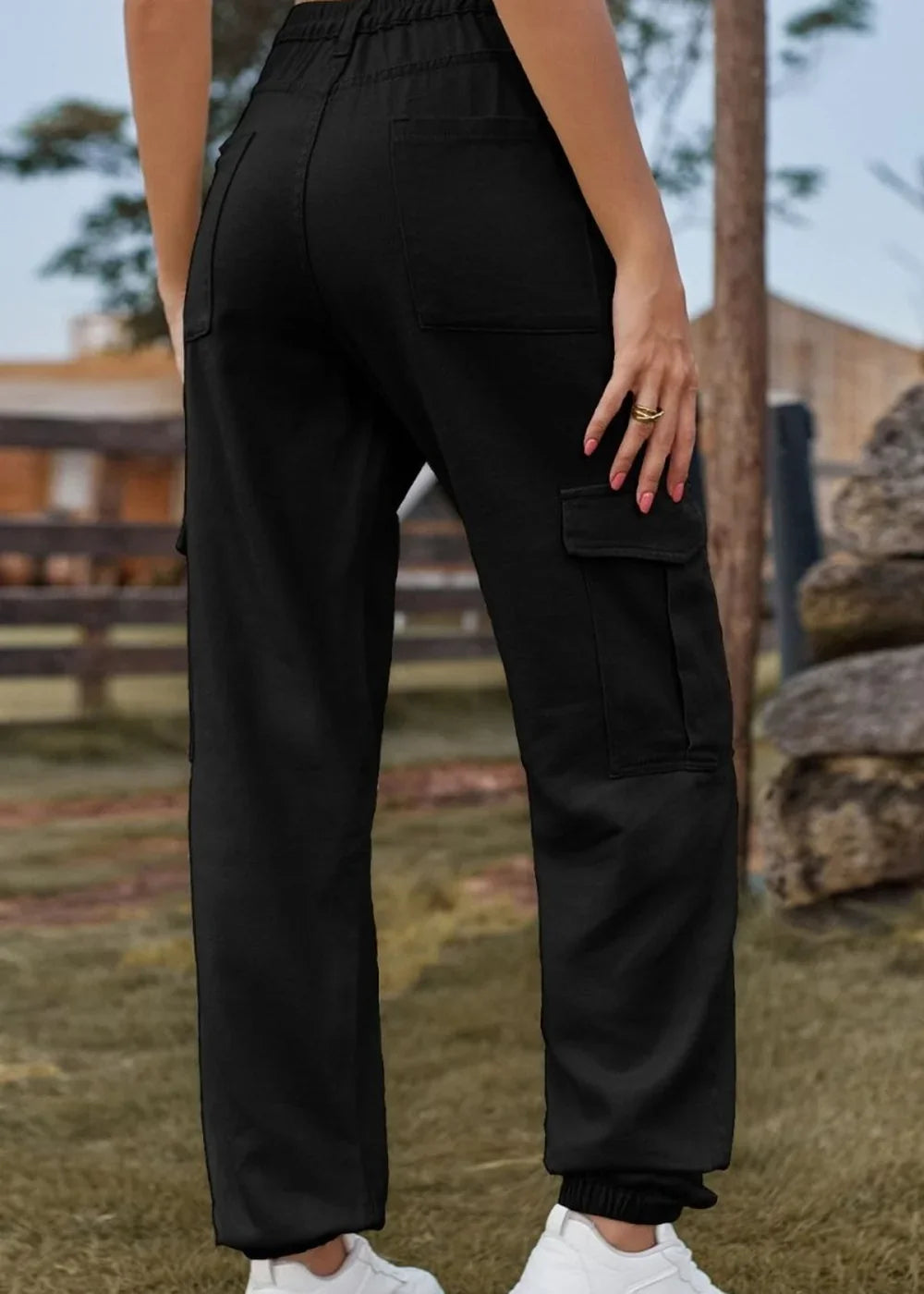 Black cargo pants with elastic waistband and cuffed ankles on a model.