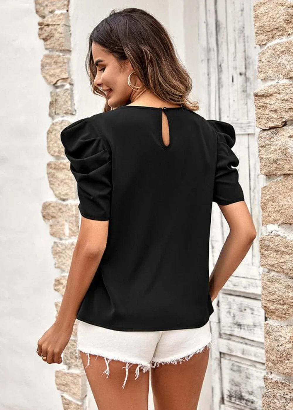 Black puff-sleeve top with a keyhole back, paired with white frayed-hem shorts on a model.