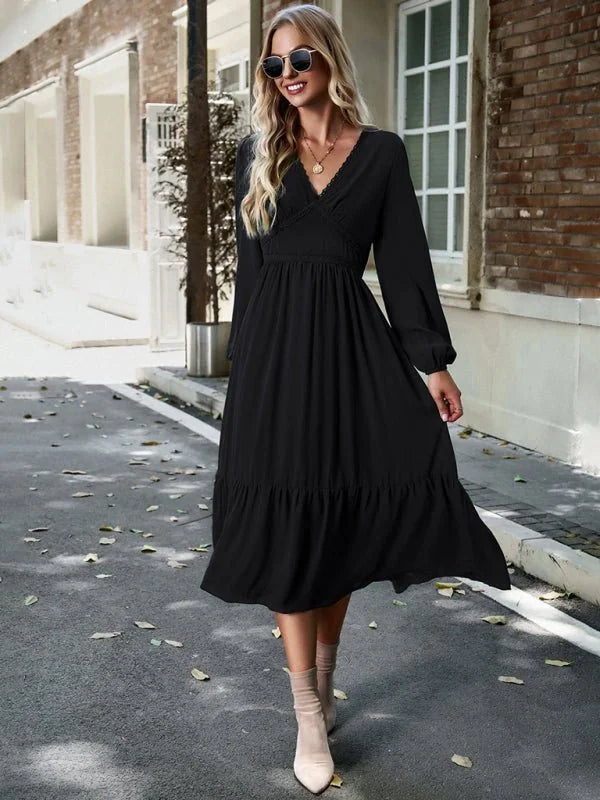 Black midi dress with V-neck, long sleeves, tiered skirt, and ankle boots on model.