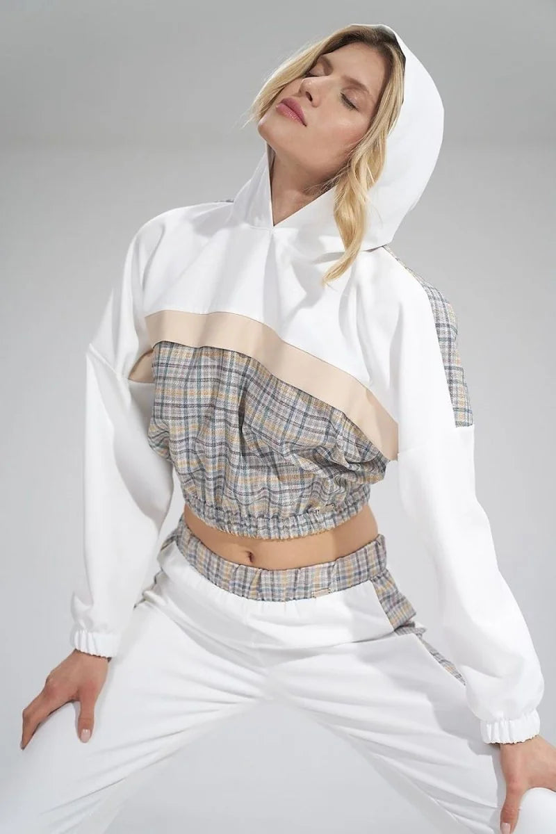 White cropped hoodie with plaid detail and tan trim, worn with matching white pants.