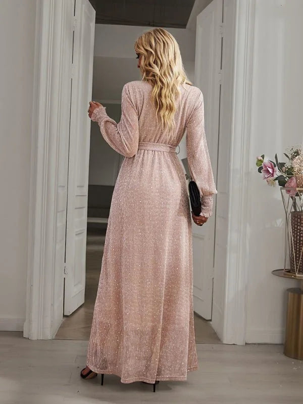 Sparkly rose gold maxi dress with long sleeves, belted waist, and a flowing skirt, shown from the back.