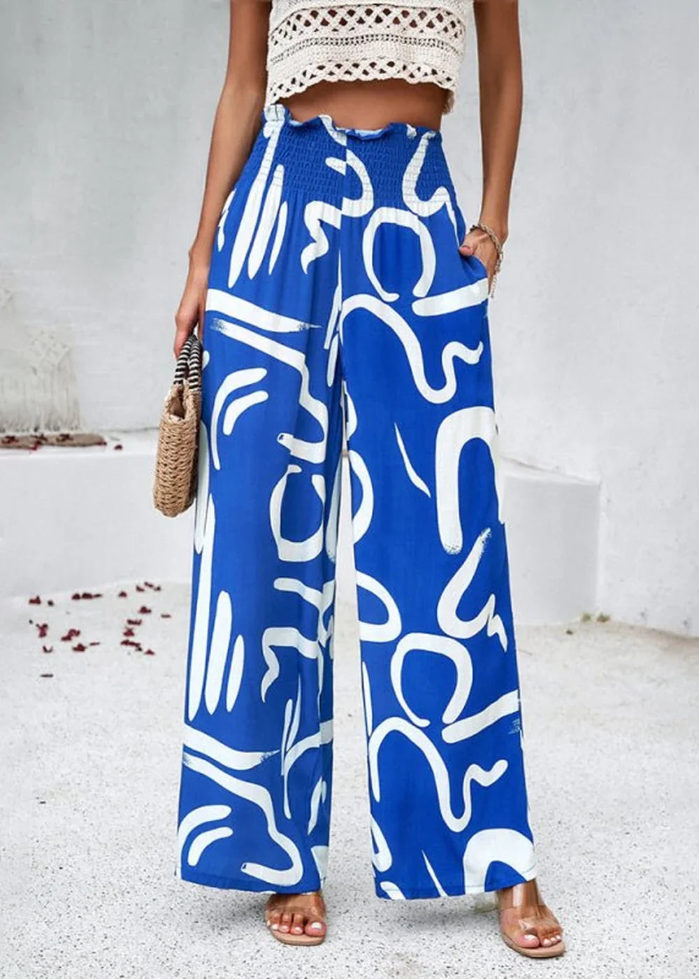 Flowy blue wide-leg pants with a white abstract print and smocked waistband.