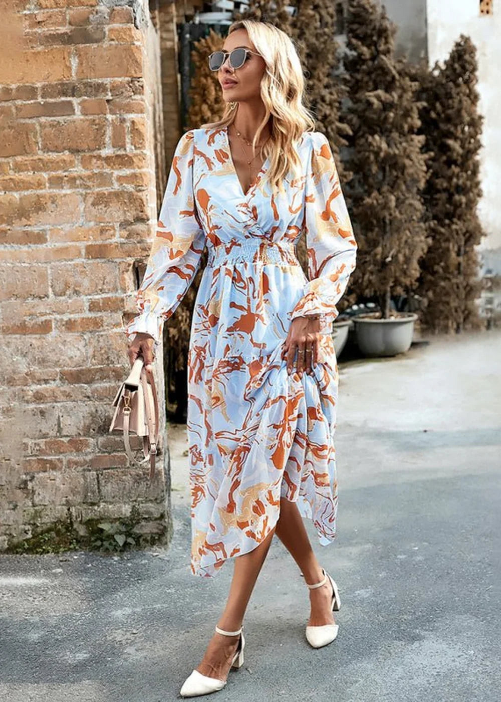 Light blue maxi dress with orange abstract print, V-neck, long sleeves, cinched waist, on model.