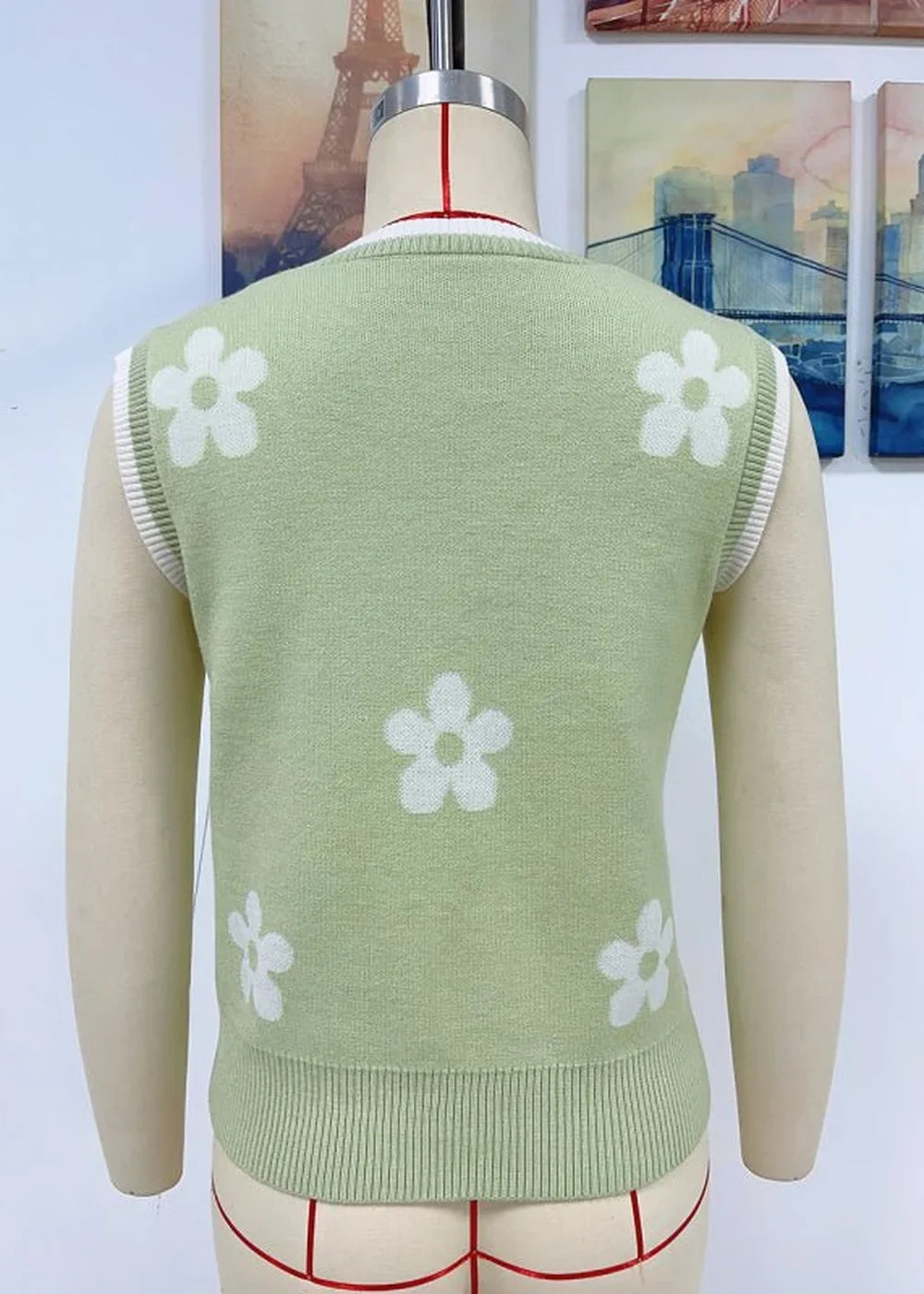 Light green knit vest with a white floral pattern and white trim.