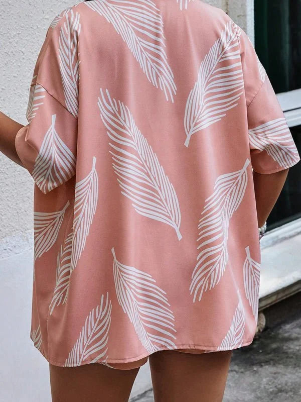 Pink short suit with white feather print, short sleeves, and a loose fit.