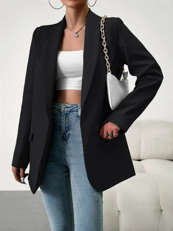 Black polyester blazer with gold chain detail on a white textured handbag, worn by a model with light wash jeans.