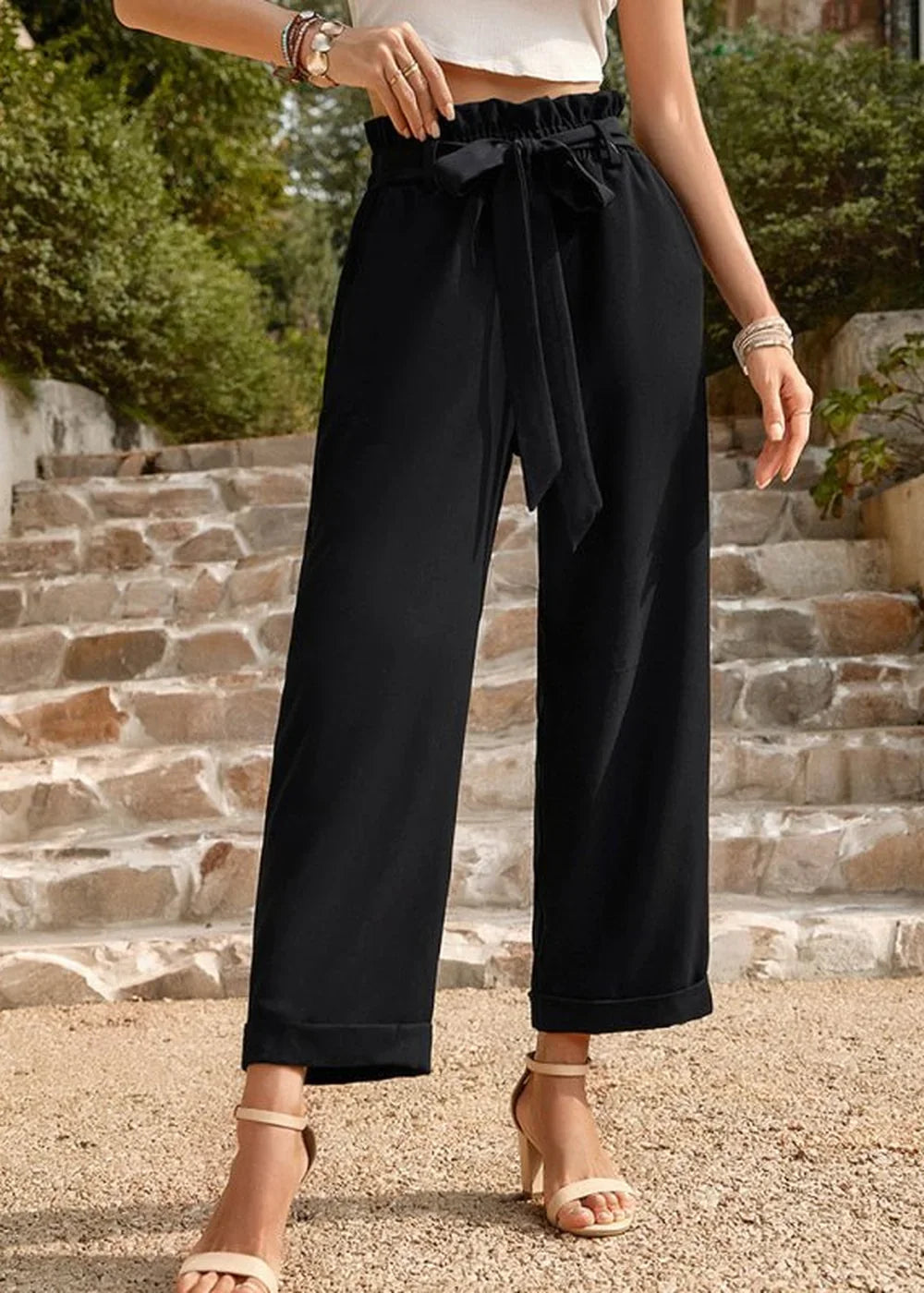Black wide-leg pants with a tie waist and beige heeled sandals on model.