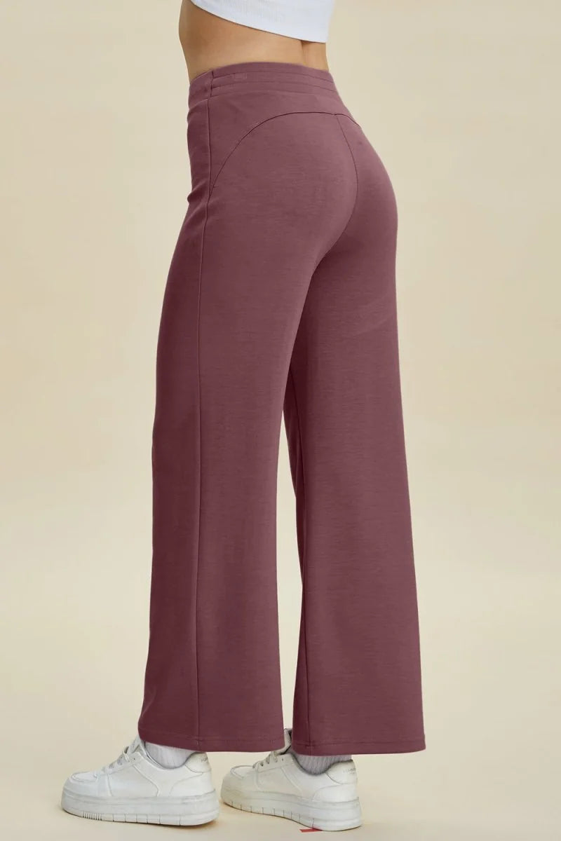 Dusty rose wide-leg pants with a flattering curved seam at the back, shown with white sneakers.