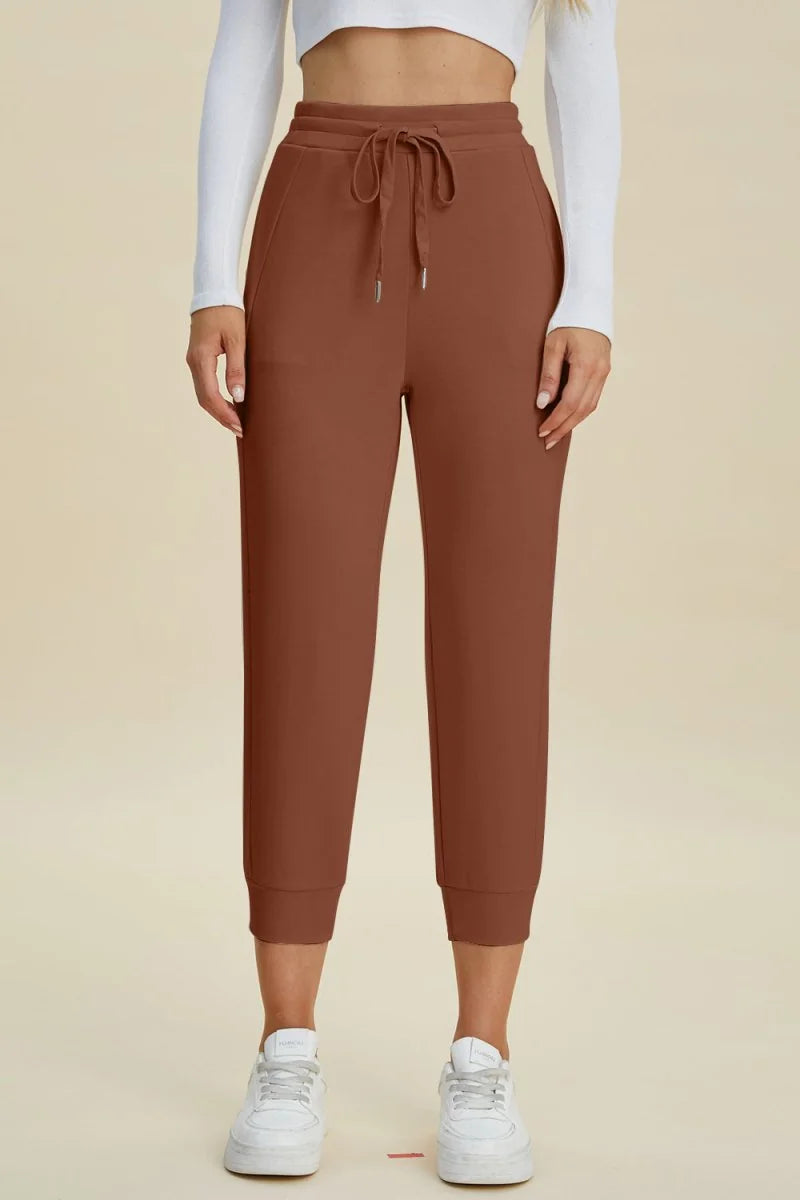 Caramel-colored joggers with a drawstring waist and cuffed ankles on a model.