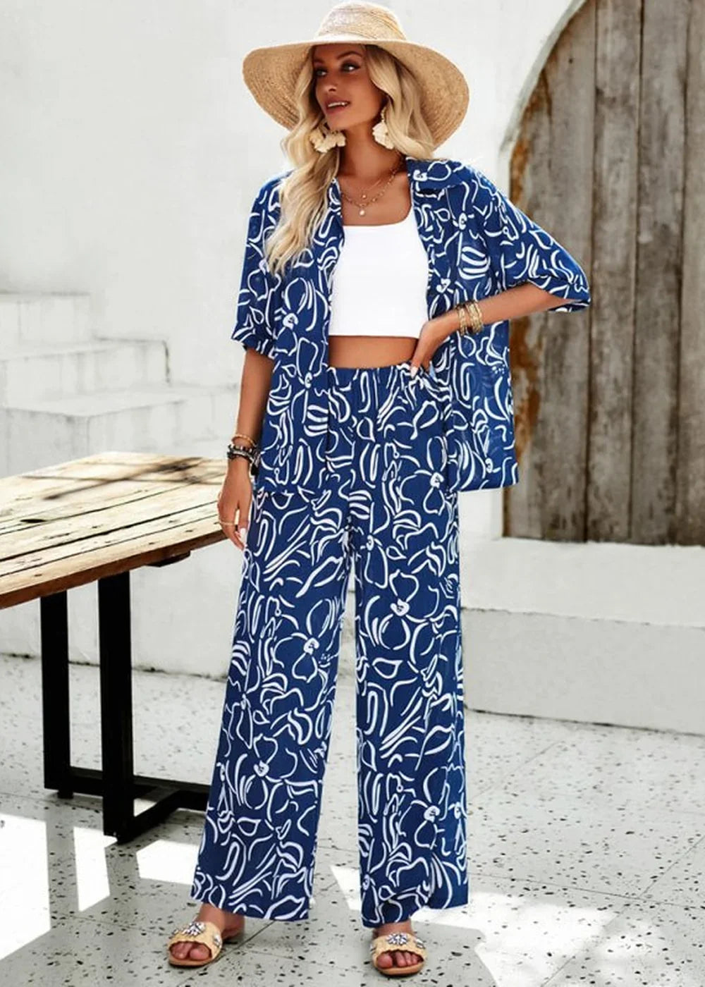 Navy blue and white floral print viscose pant suit with straw hat and white crop top on model.