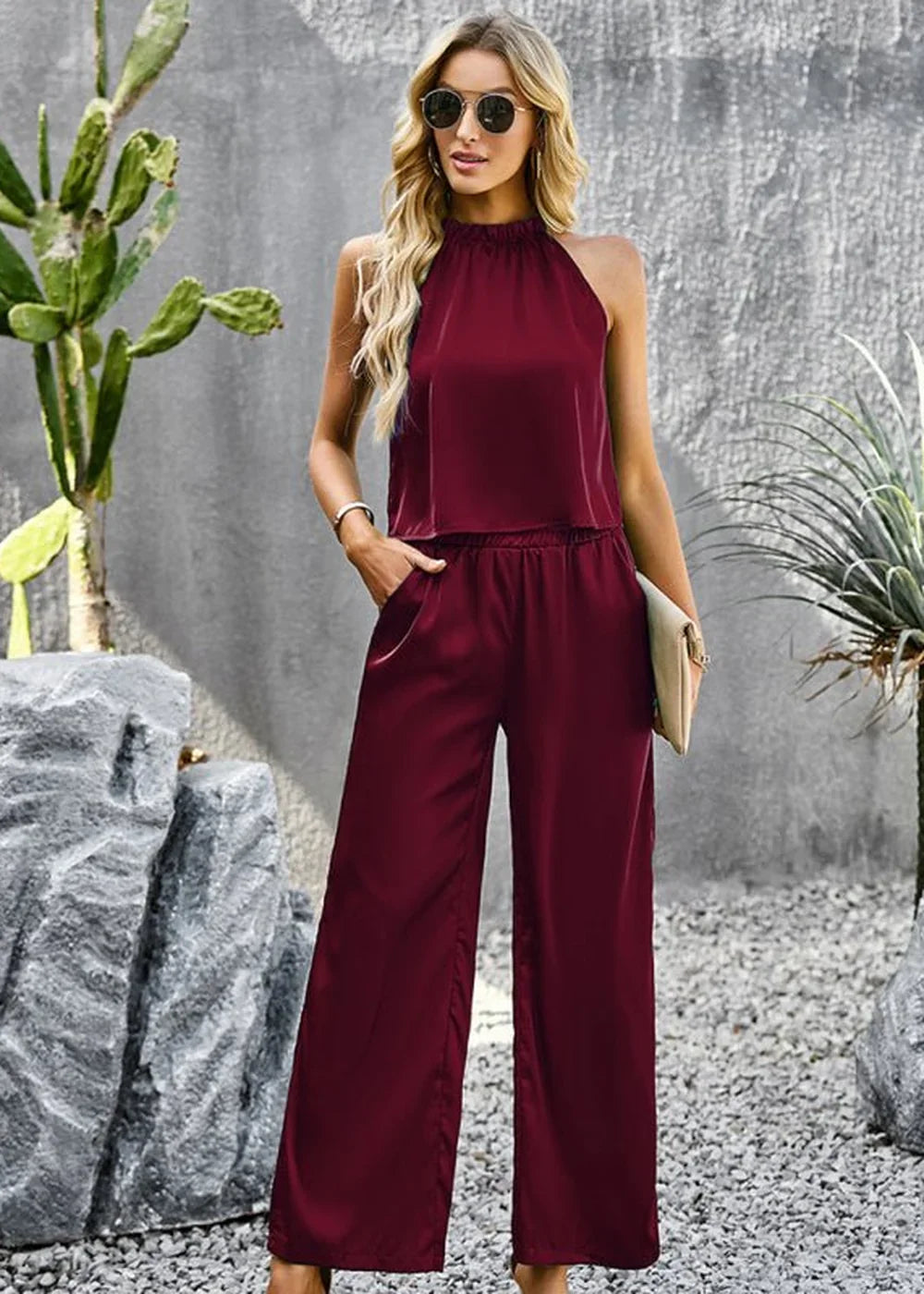 Burgundy sleeveless wide-leg jumpsuit with a halter neckline and elastic waist, worn by a model.