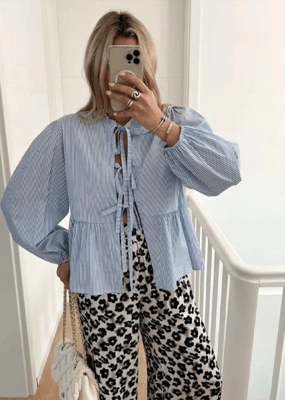 Blue and white striped peplum top with tie detail and leopard print pants on model.