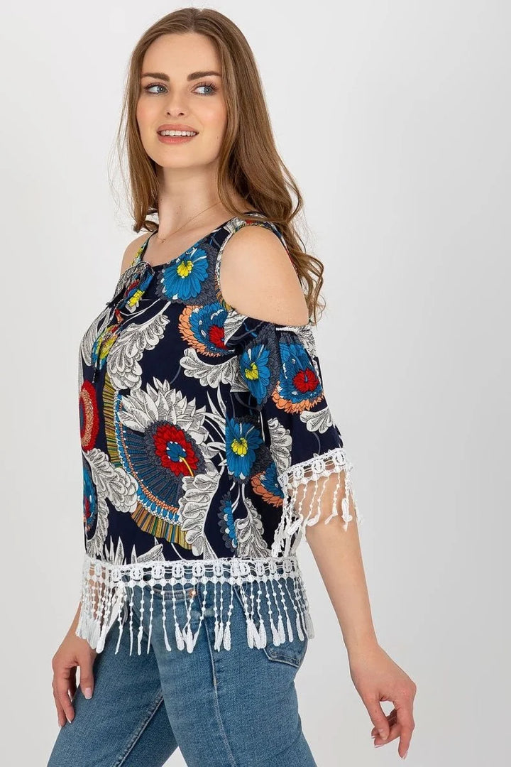 Navy blue cold-shoulder top with vibrant floral print and white fringe trim.