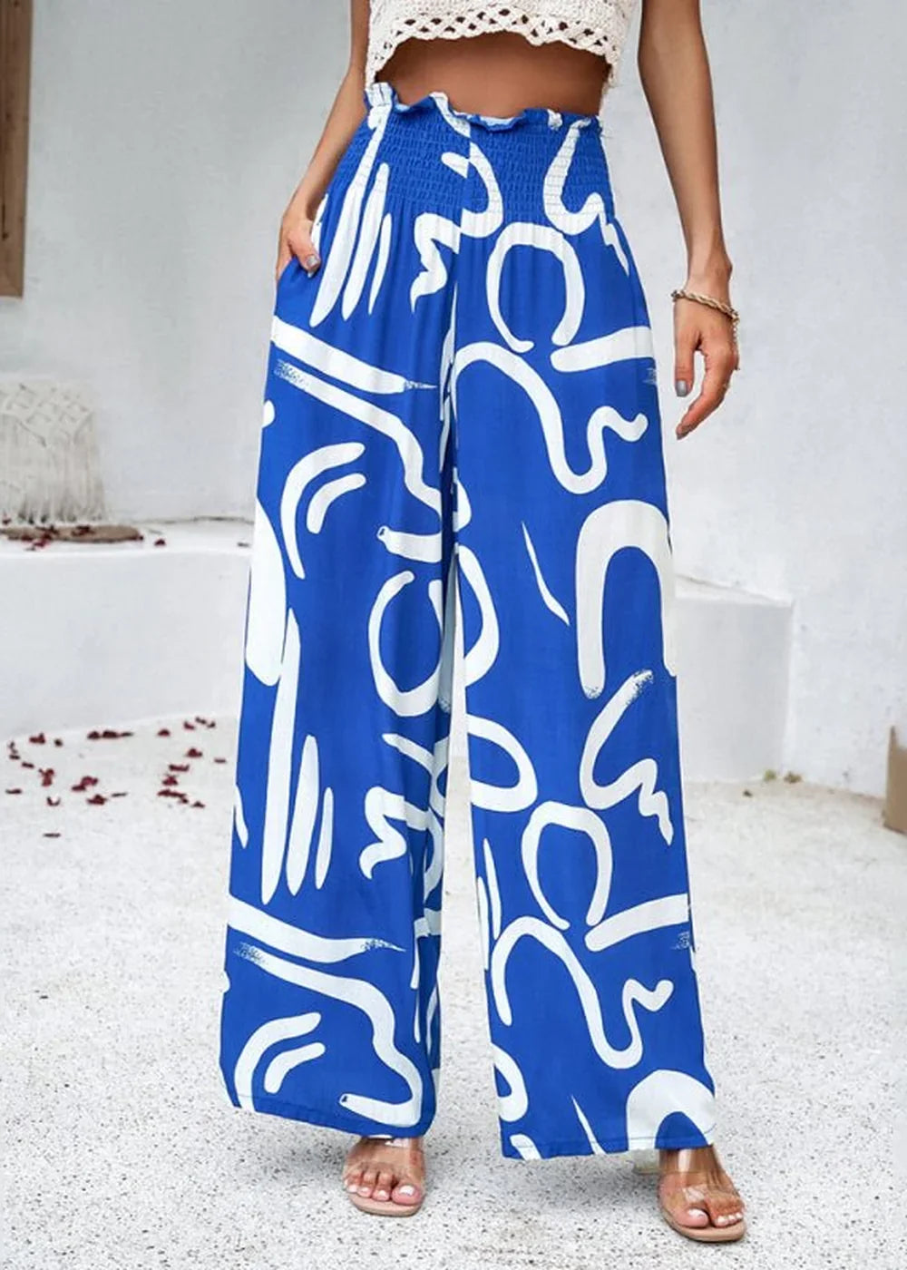 Blue wide-leg pants with white abstract print and smocked waist.
