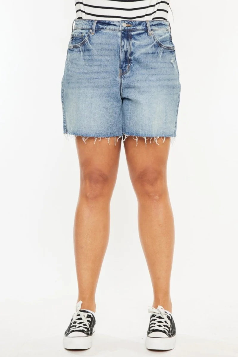 Light wash distressed denim shorts with a frayed hem, worn by a model with black platform sneakers.