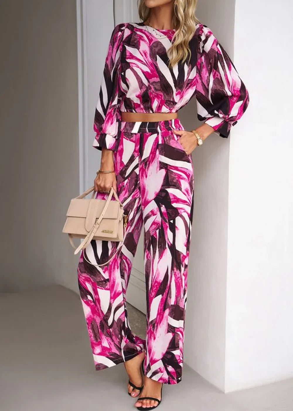 Woman in a vibrant pink, white, and dark print matching crop top and wide-leg pants.