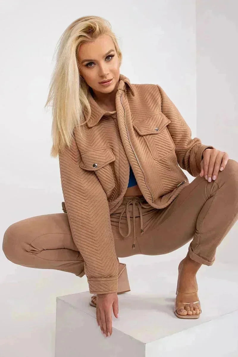 Quilted beige jacket with chevron pattern and zip closure, worn by a woman crouching.