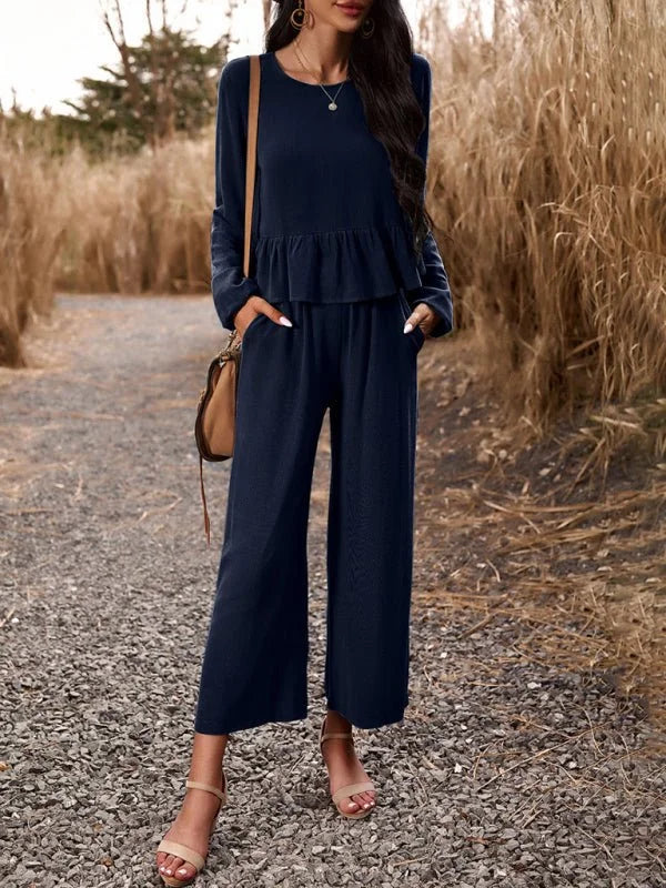 Navy blue linen-blend cropped pantsuit with a peplum top and ankle-strap sandals.