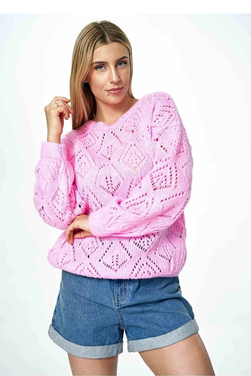 Pink knit sweater with a diamond pattern and rolled-up denim shorts on a model.