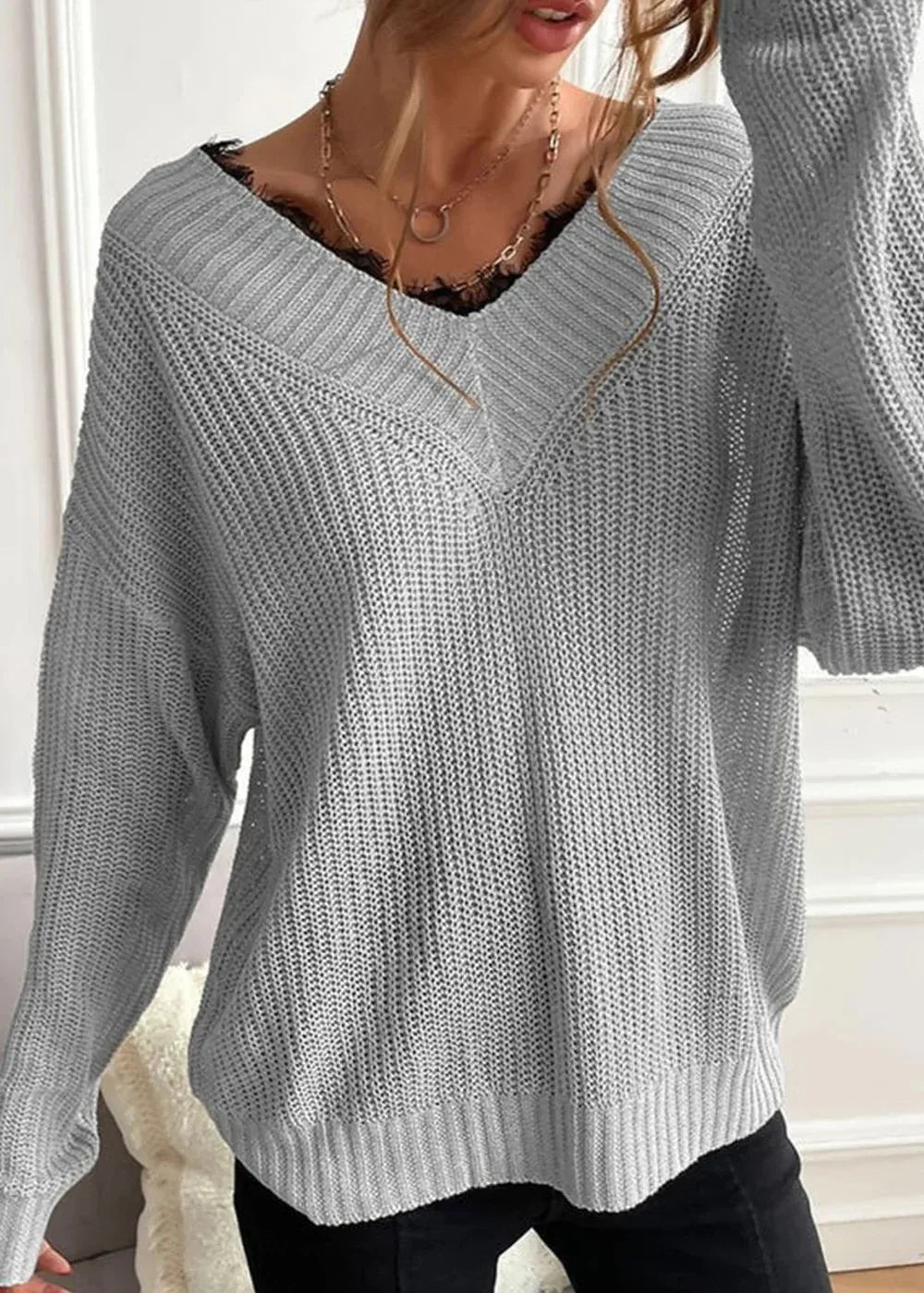 Grey knit sweater with a V-neck and lace trim detail.