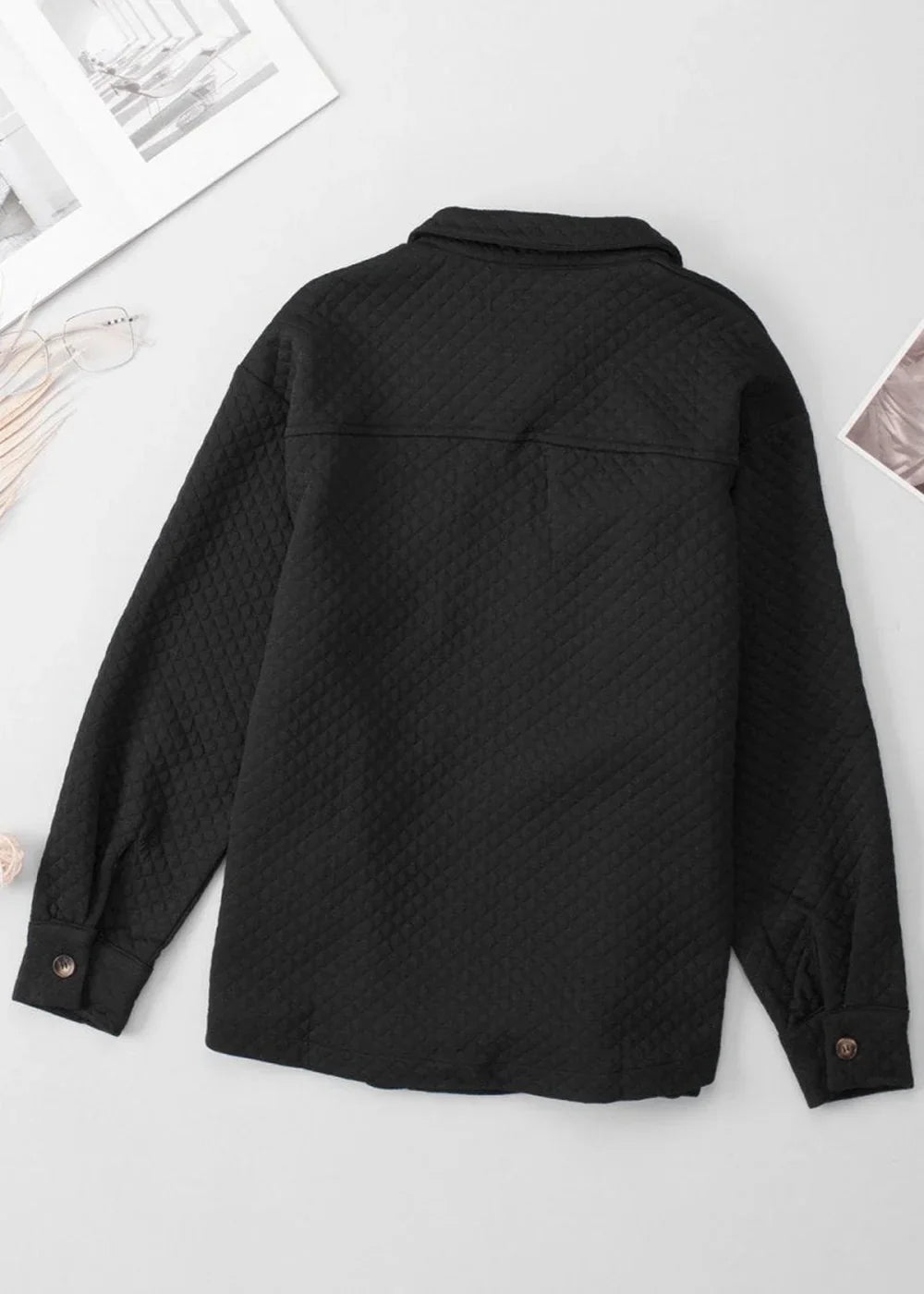 Black quilted shirt jacket from the back, showing button cuffs and collar.