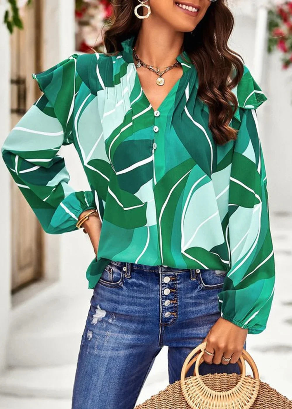 Green and light green abstract leaf print blouse with ruffle sleeves and button front on model.