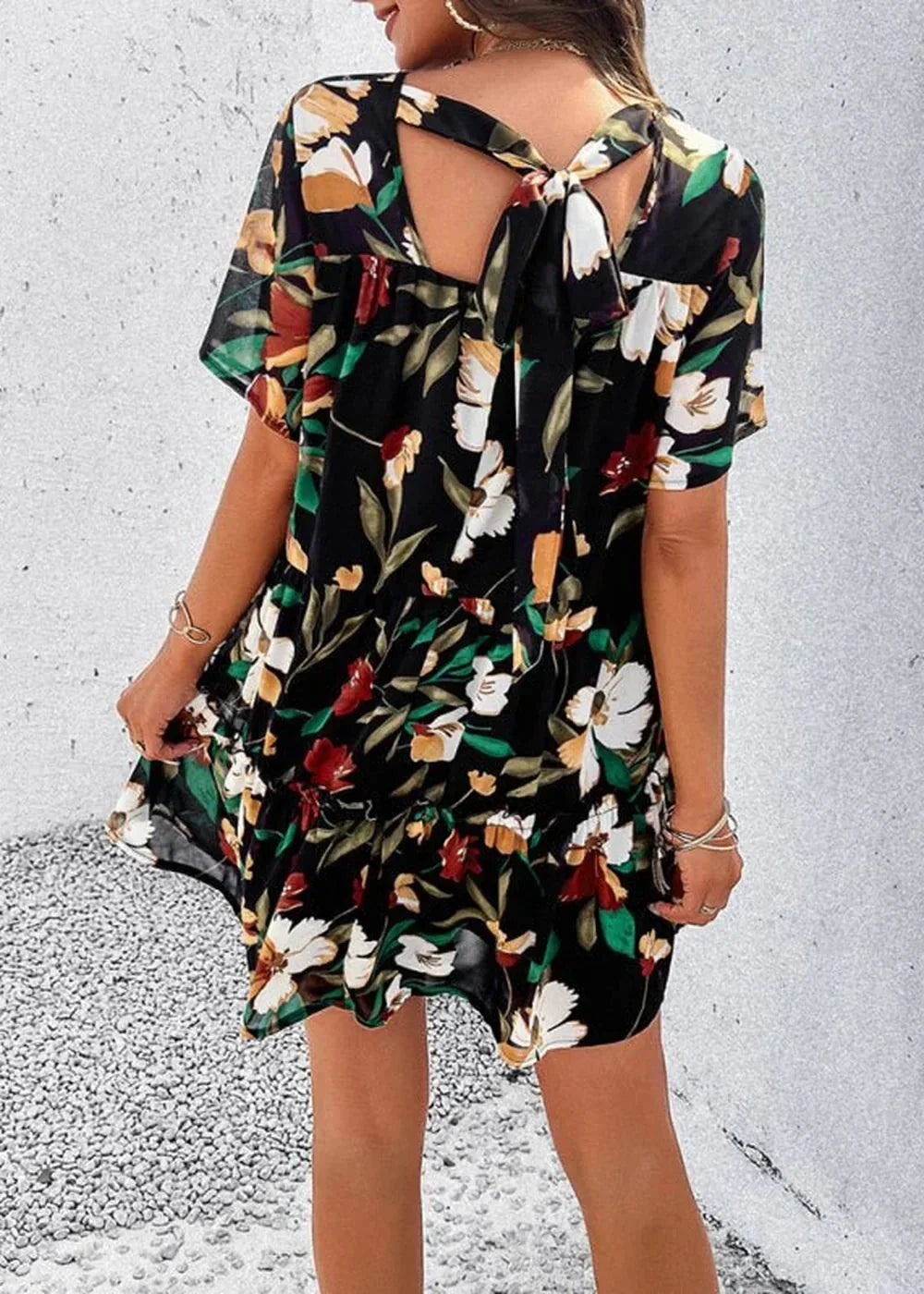 Black floral print dress with a tie-back detail and ruffled hem, on model.