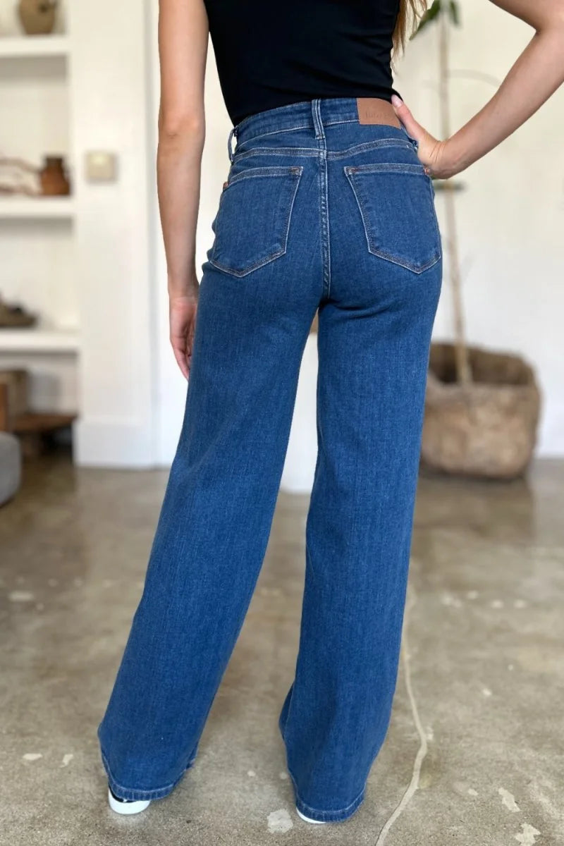 Back view of wide-leg, dark wash denim jeans on a model.
