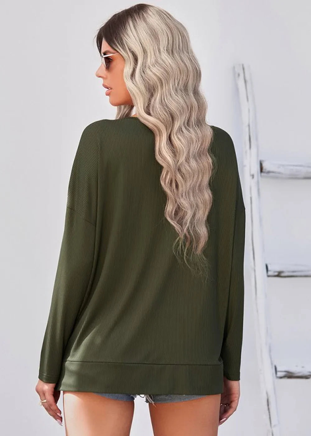Back view of a woman wearing a dark olive green ribbed long-sleeve top.