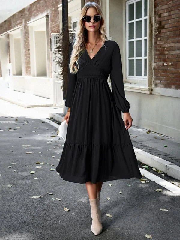 Black midi dress with V-neck, long sleeves, and tiered skirt on model.