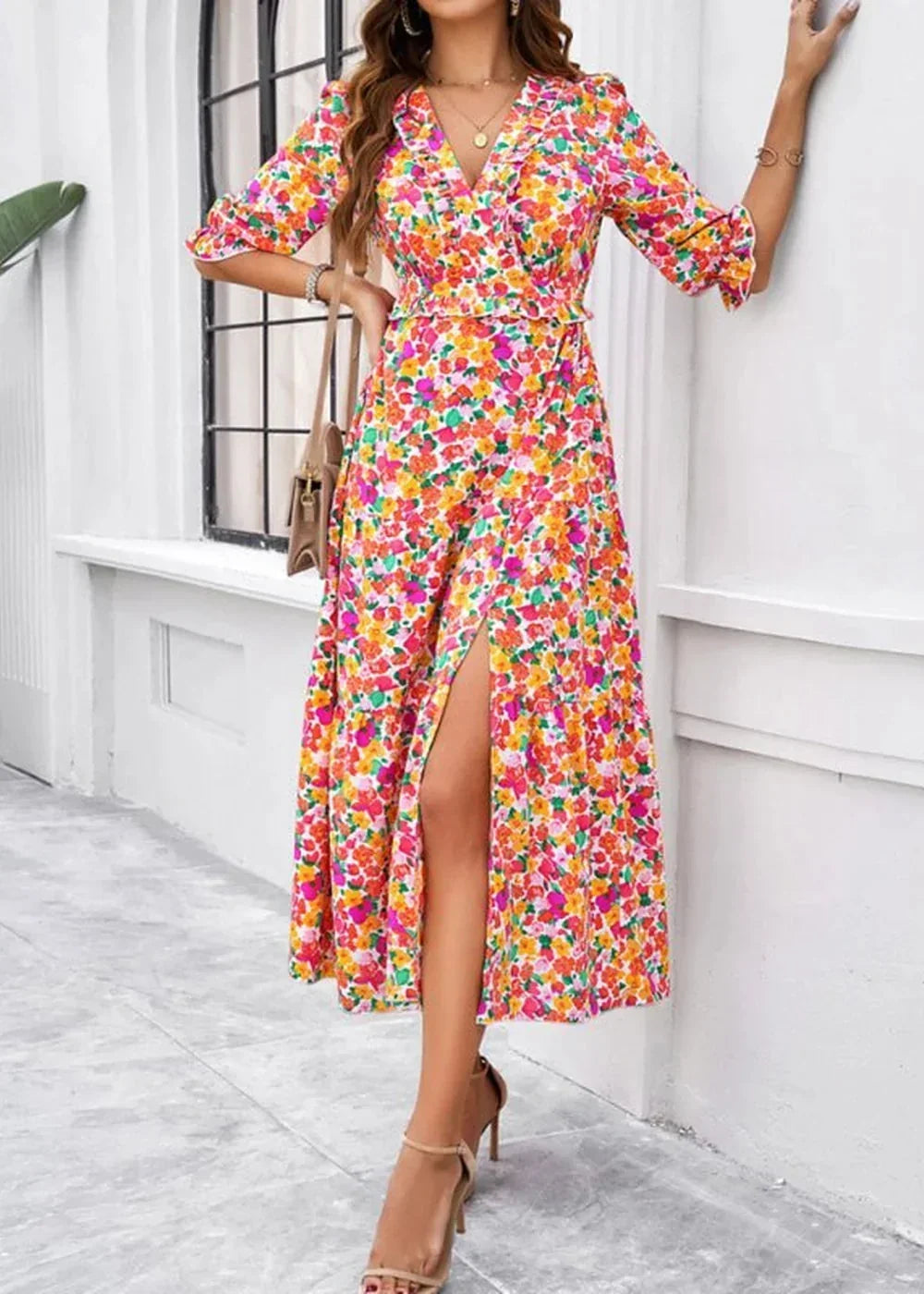 A vibrant floral print wrap dress with a high slit and ruffle trim, shown on a model.