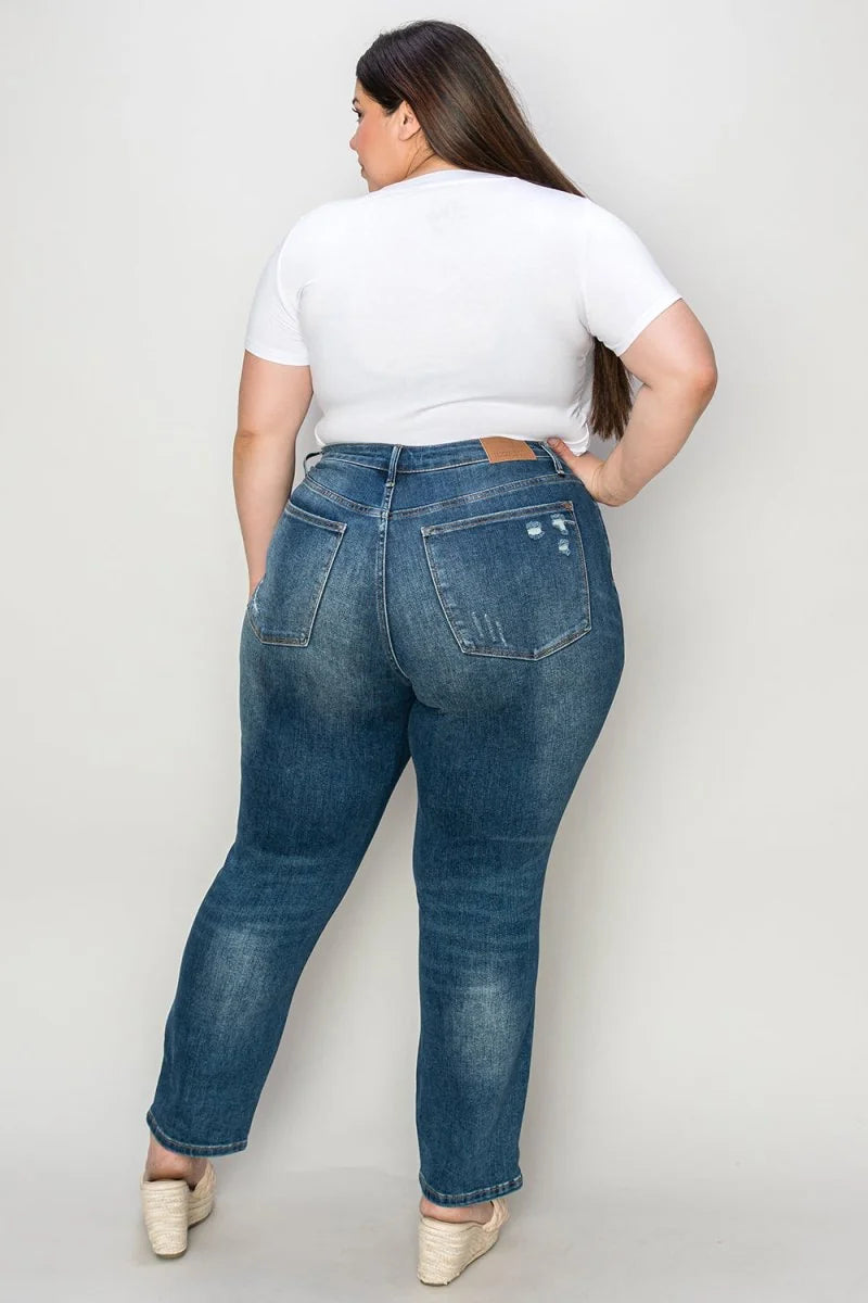 Woman from behind wearing distressed medium-wash jeans with a white t-shirt and tan wedge sandals.