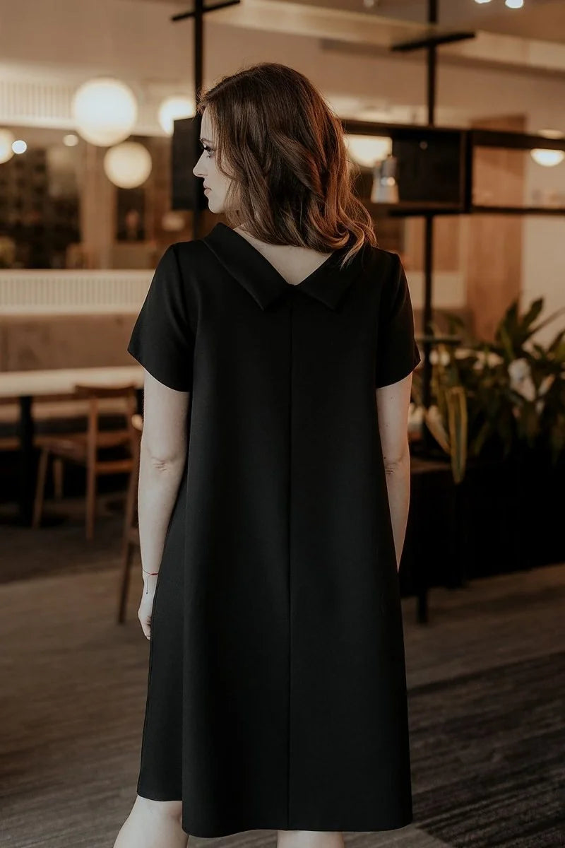 Back view of a loose-fit black day dress with short sleeves and a Peter Pan collar.